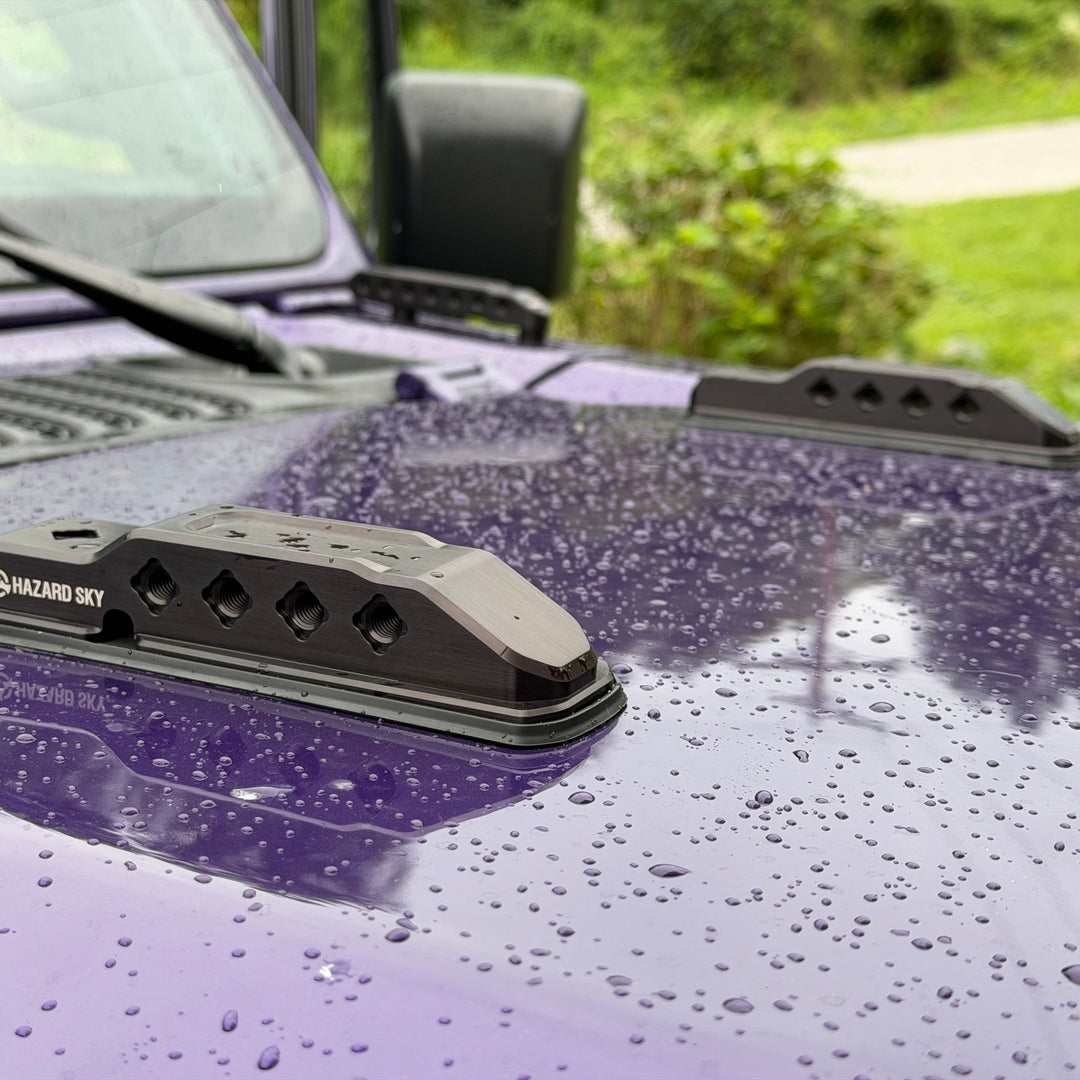 Pair of black HazardKey billet hood bumpers installed on the hood of a purple Jeep Wrangler JL