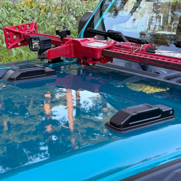 Black billet aluminum hood bumpers installed on the hood of a teal Jeep Wrangler JL